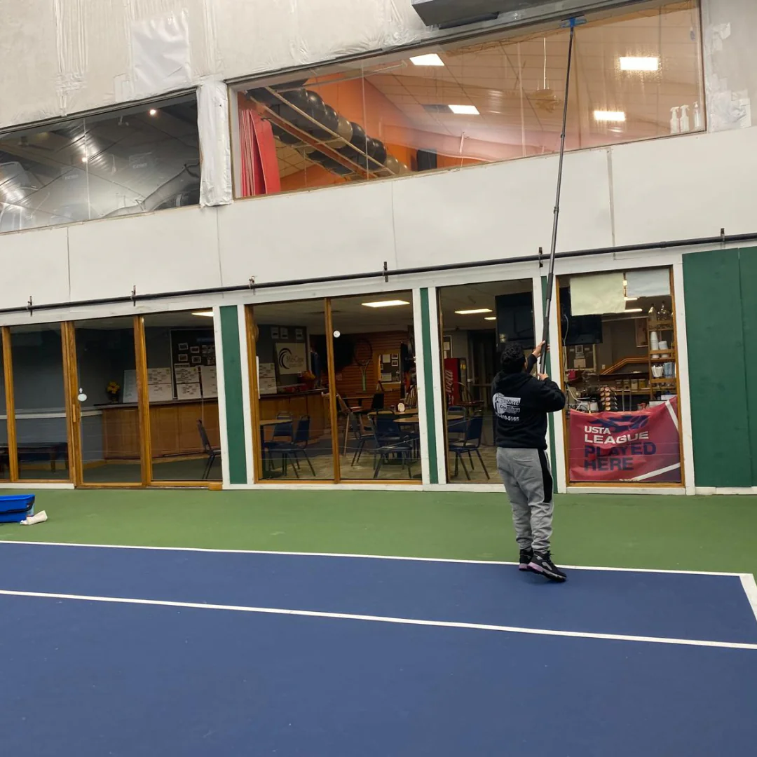 Sentinel crew cleaning high interior glass at an indoor sports facility on Cape Cod