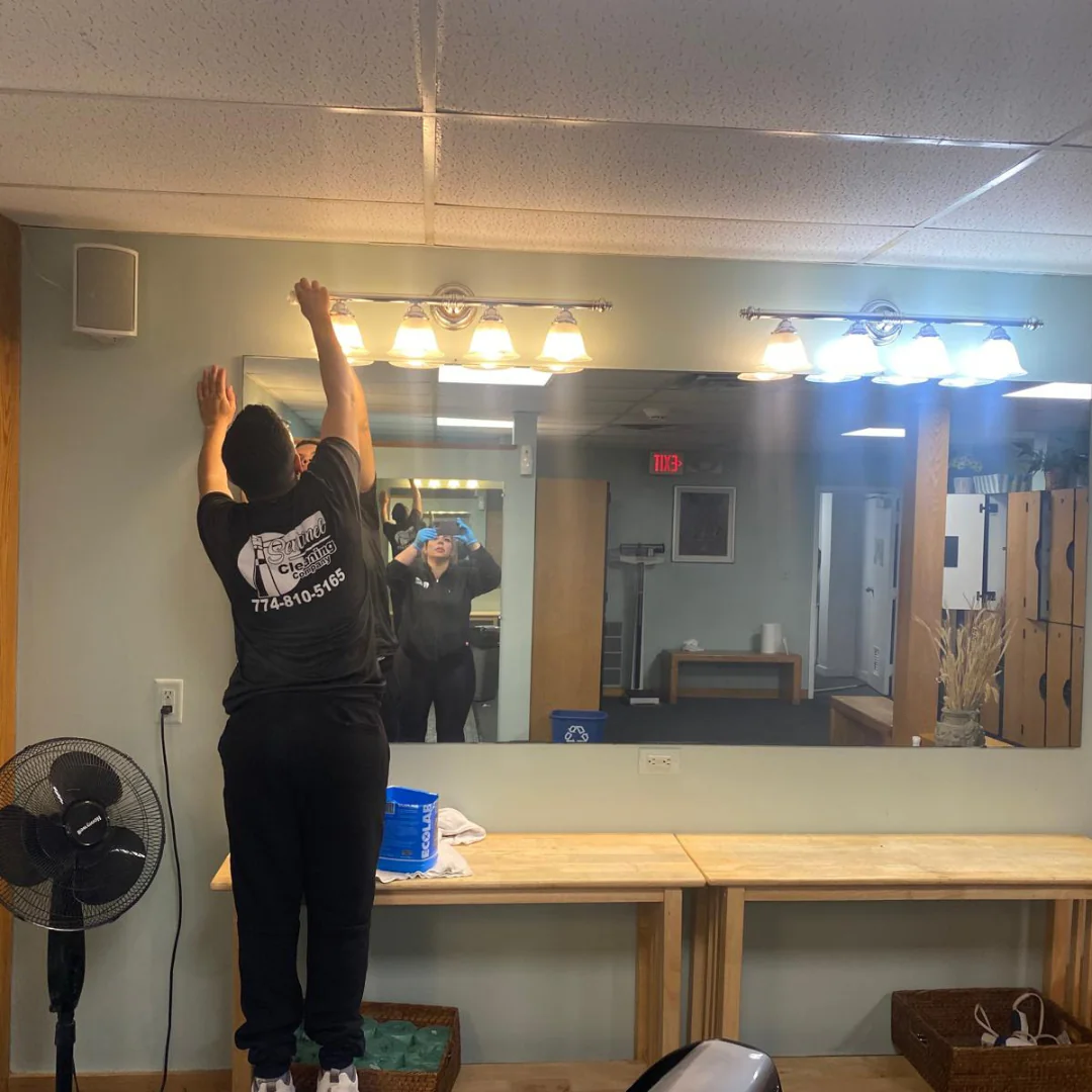 Sentinel team member cleaning locker room mirrors at a Cape Cod facility